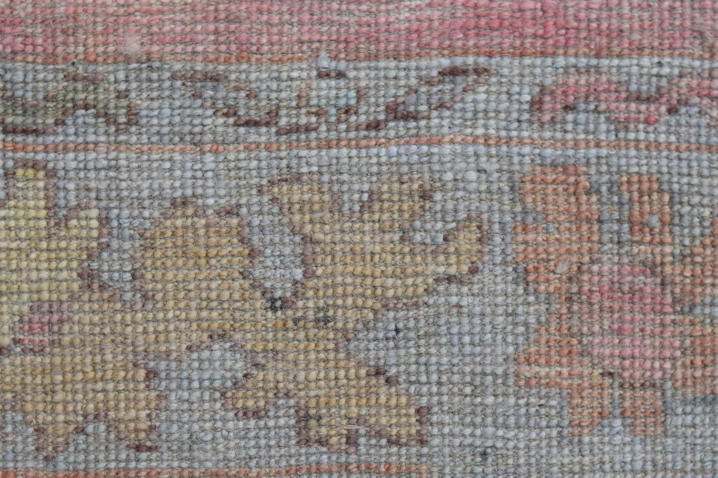 A close-up view of a handwoven wool runner featuring a faded floral pattern in soft pastel tones.