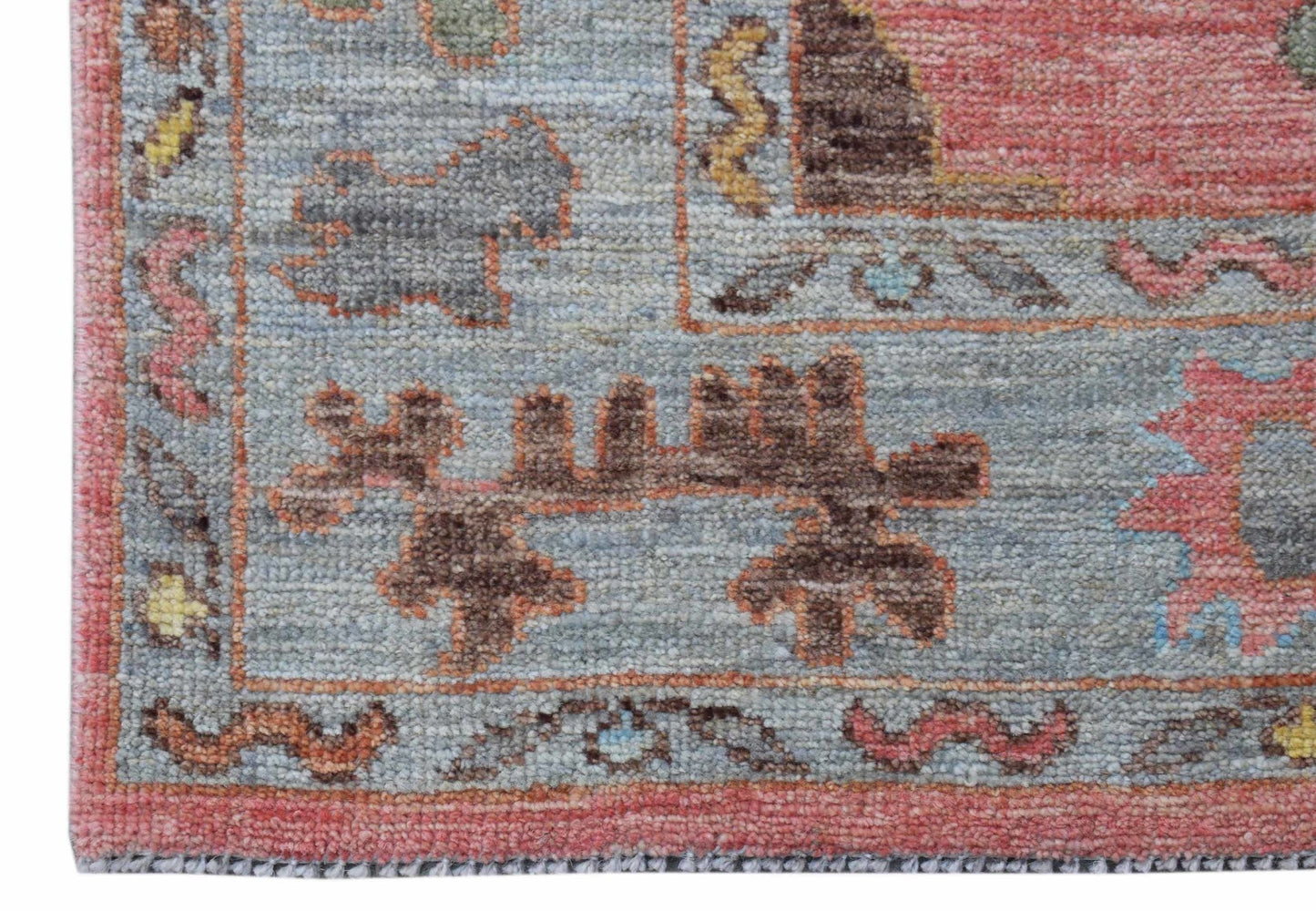 A close-up of a handwoven transitional Oushak runner featuring floral motifs in muted tones.