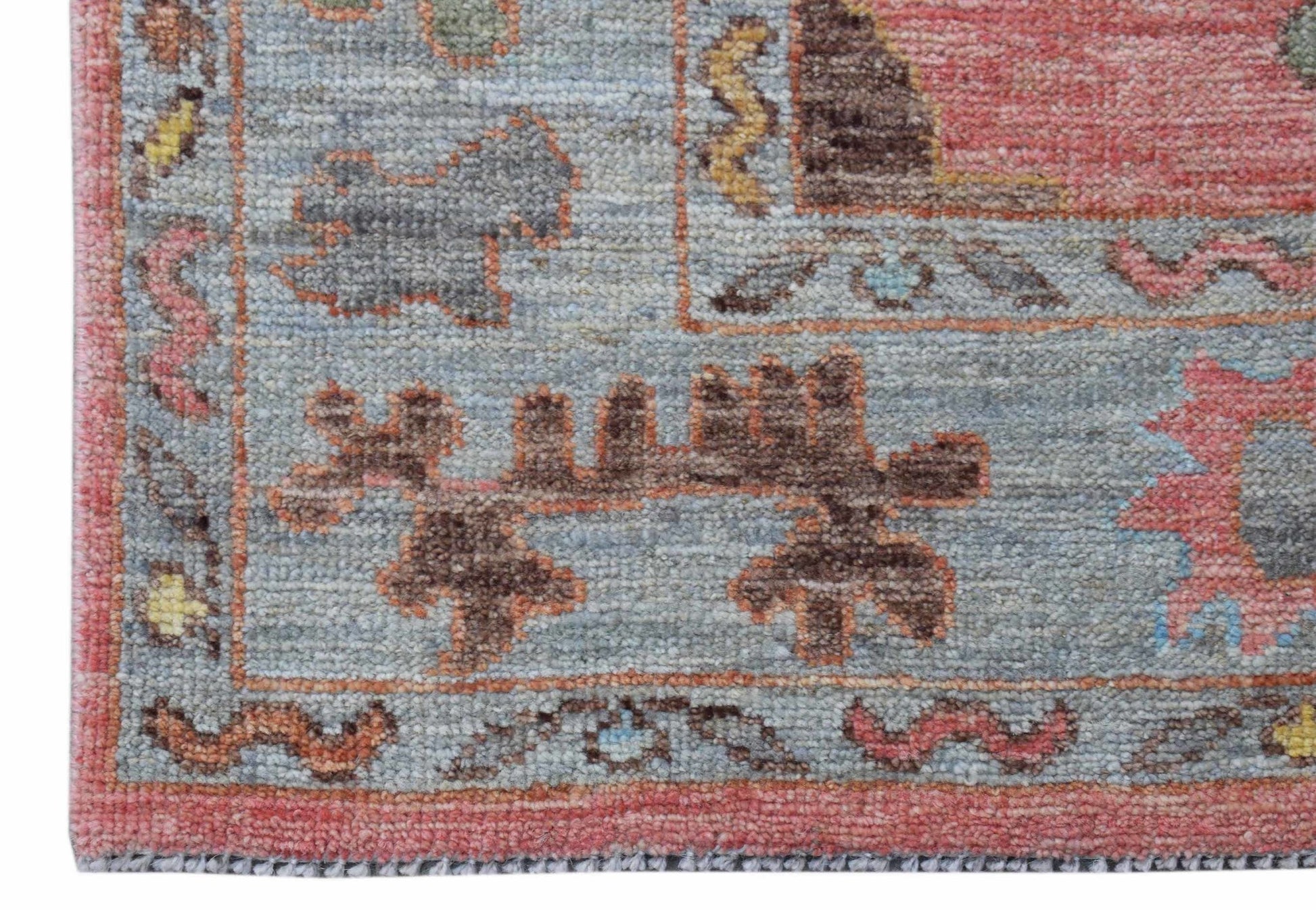 A close-up of a handwoven transitional Oushak runner featuring floral motifs in muted tones.