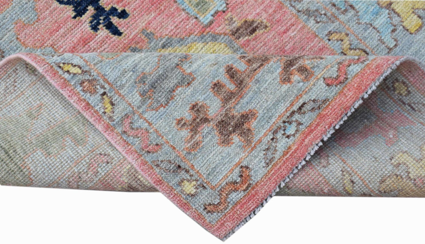 A handwoven transitional Oushak runner featuring a floral pattern in soft pink and blue tones.
