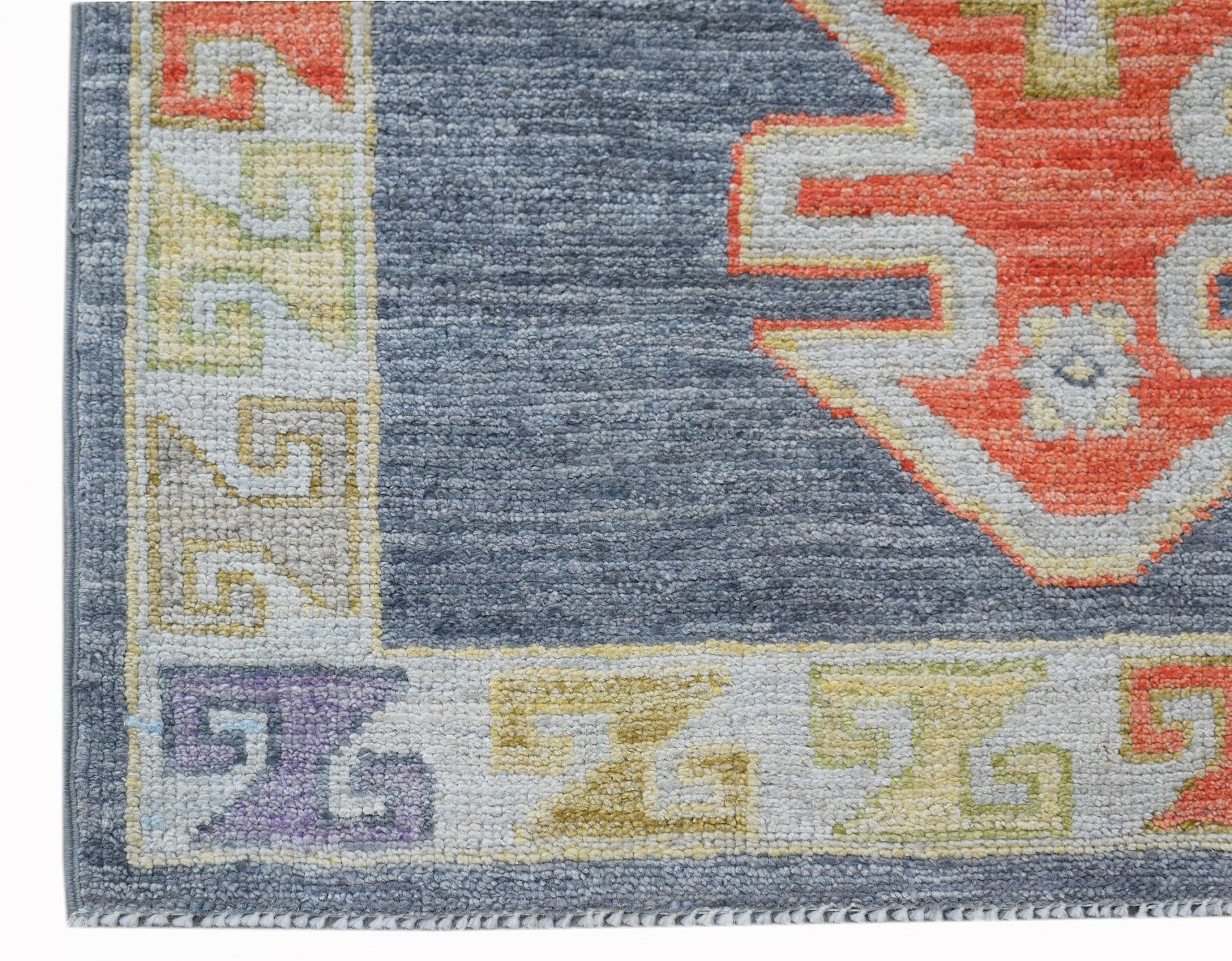 A handwoven wool runner featuring a blue field with a geometric orange and cream border pattern.