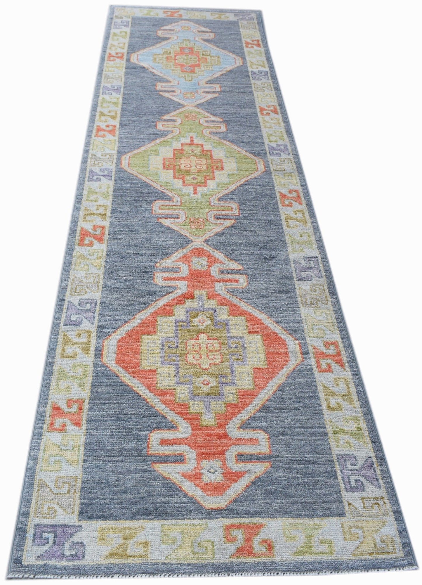 A handwoven transitional Oushak runner featuring geometric medallions on a blue field.