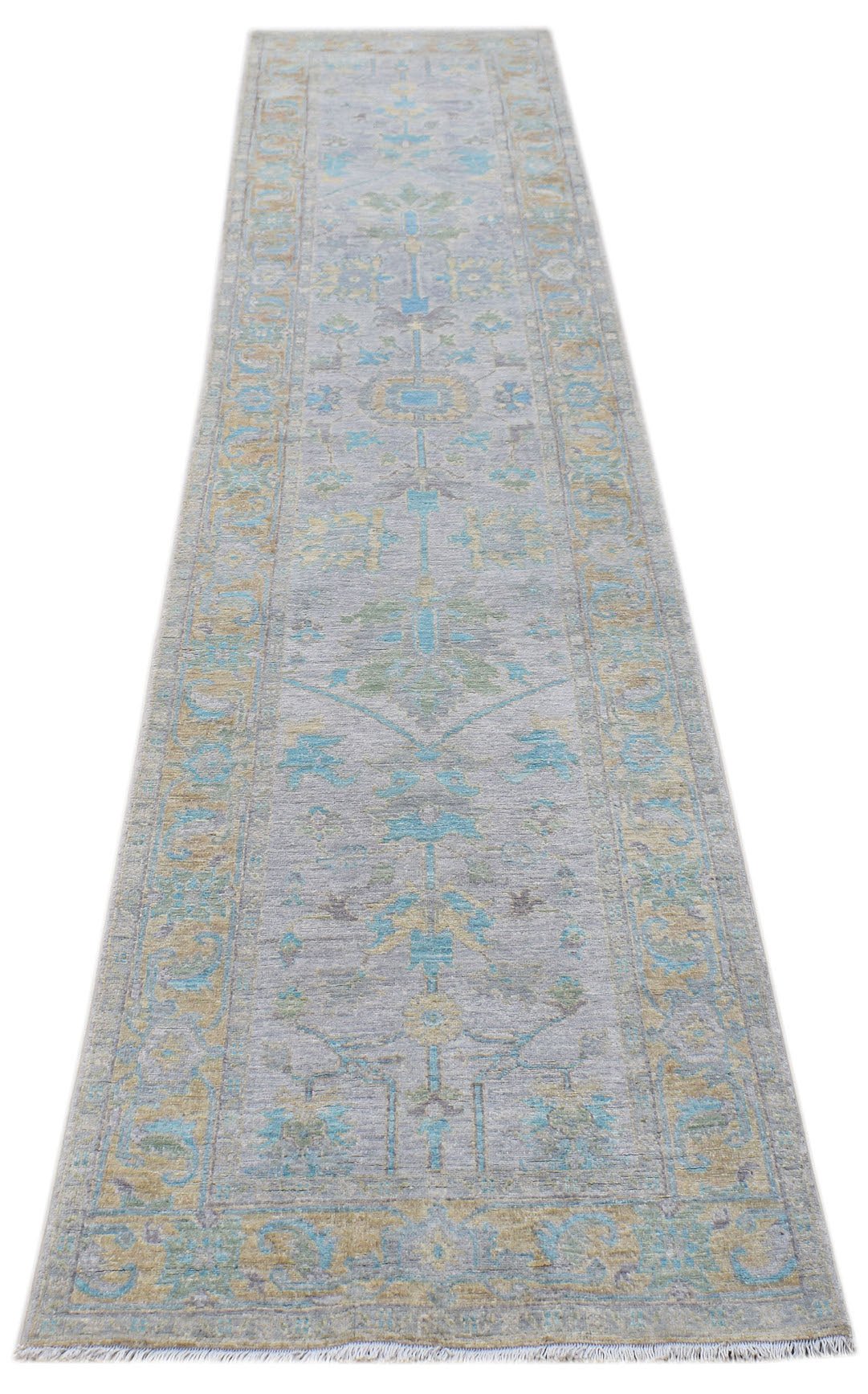 A handwoven transitional Oushak runner rug featuring a floral pattern in blue, green, and gold.