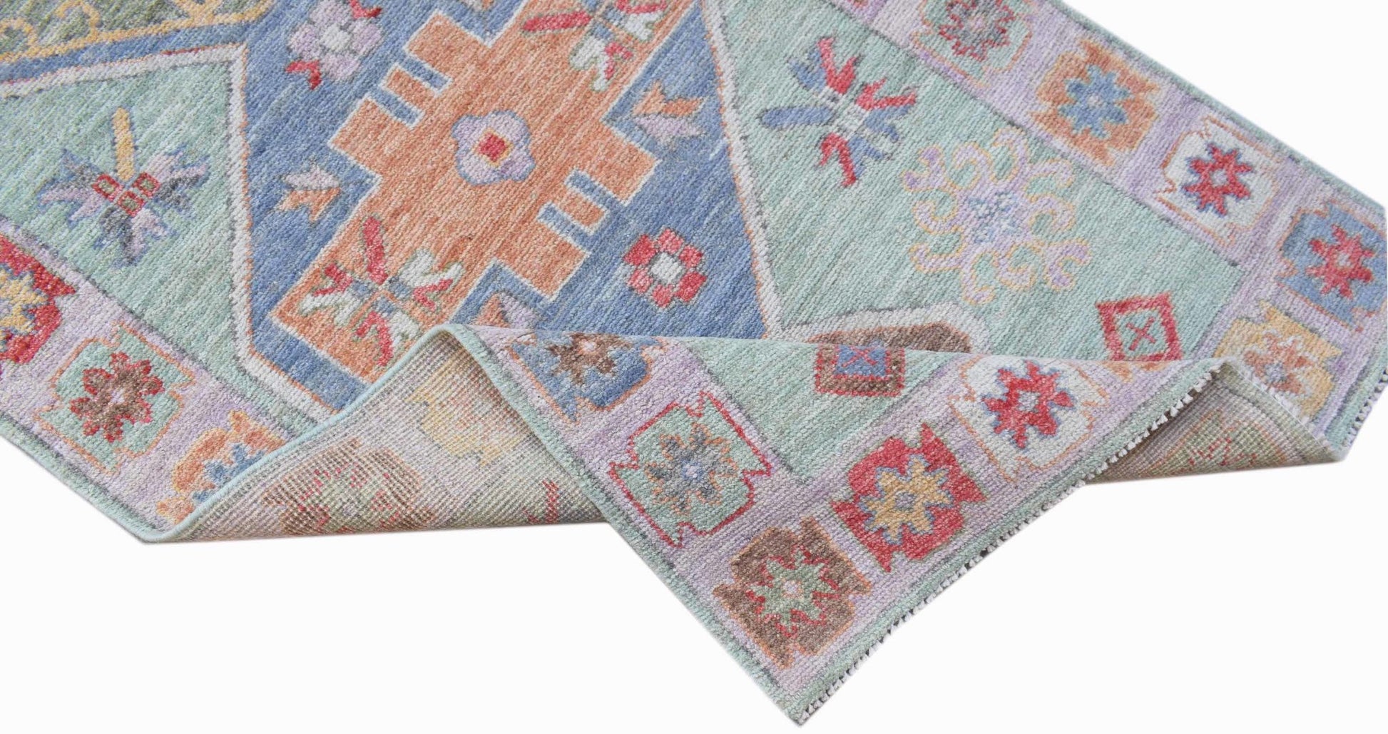 A handwoven wool runner rug featuring a transitional Oushak pattern in soft blue and pastel tones.