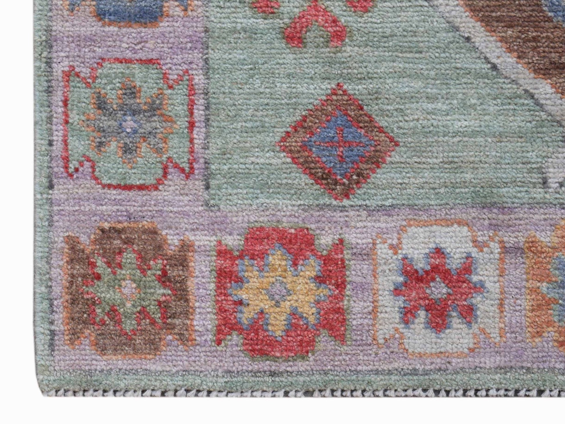 A handwoven wool runner featuring a transitional Oushak pattern in soft, multi-colored tones.