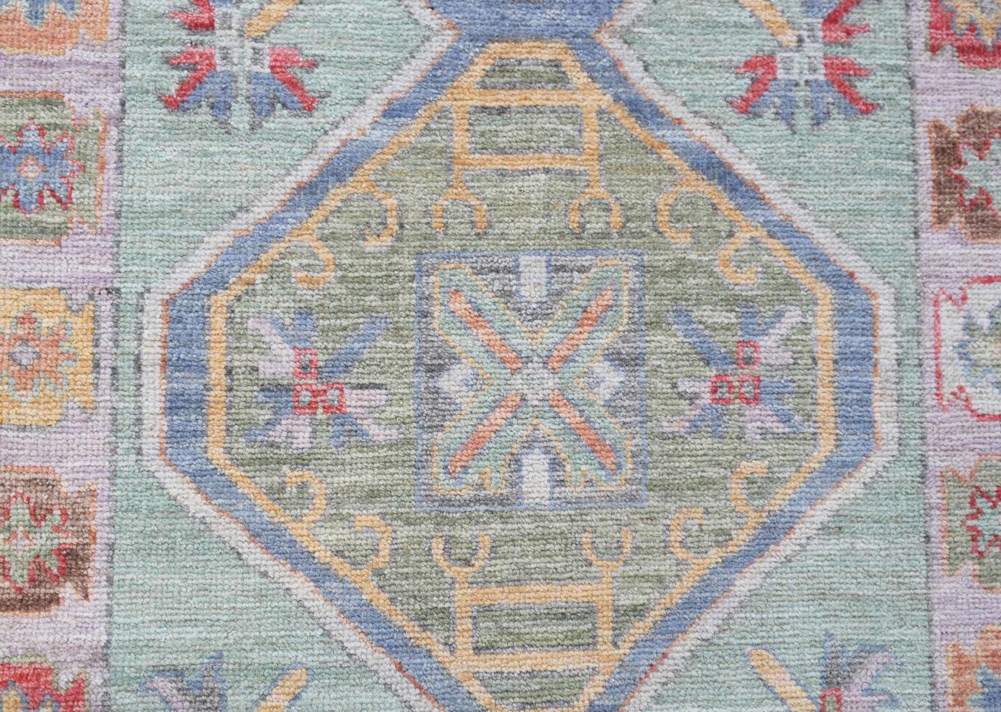 A handwoven transitional Oushak runner featuring a central geometric medallion in soft green tones.