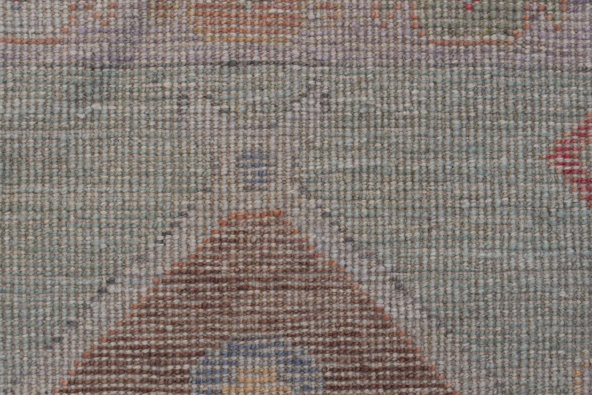 A close-up of a handwoven wool runner featuring a transitional Oushak pattern in muted tones.