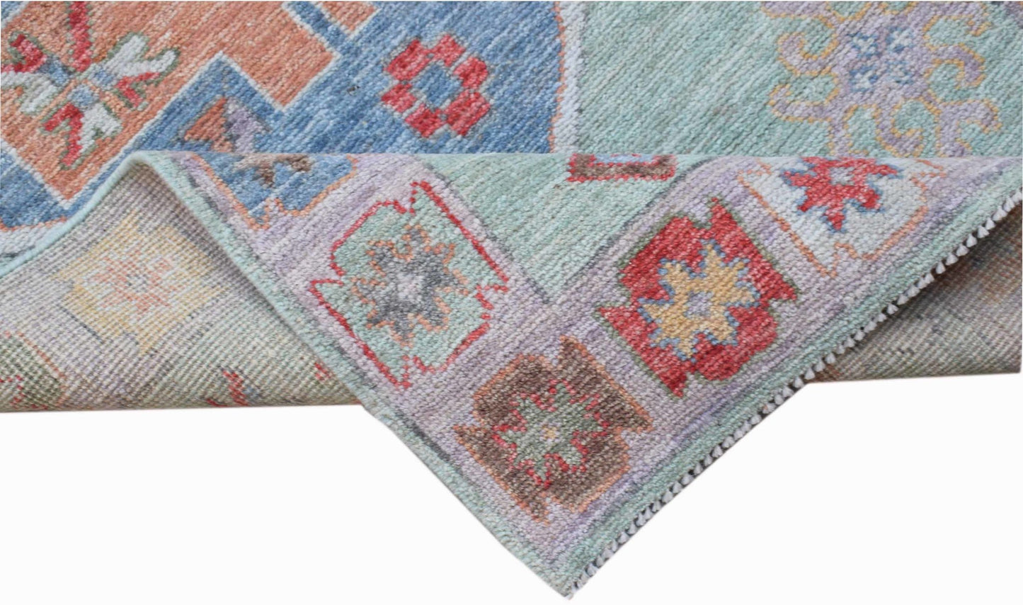 A handwoven wool runner featuring a transitional Oushak pattern in soft blue and red tones.