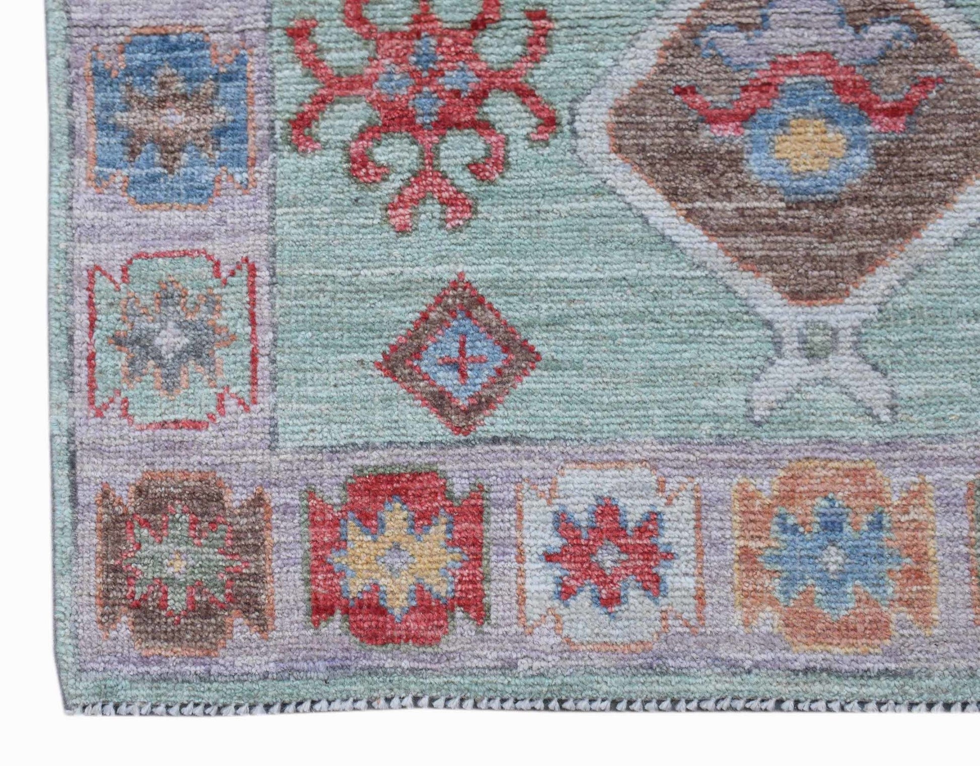 A handwoven wool runner featuring a transitional Oushak pattern in soft blue and earthy tones.