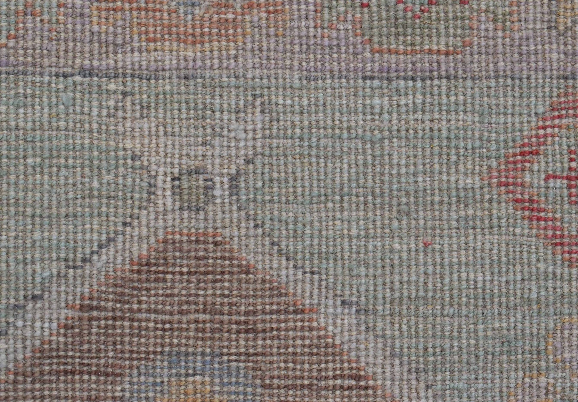 A close-up view of a handwoven wool runner featuring a transitional Oushak pattern in muted tones.