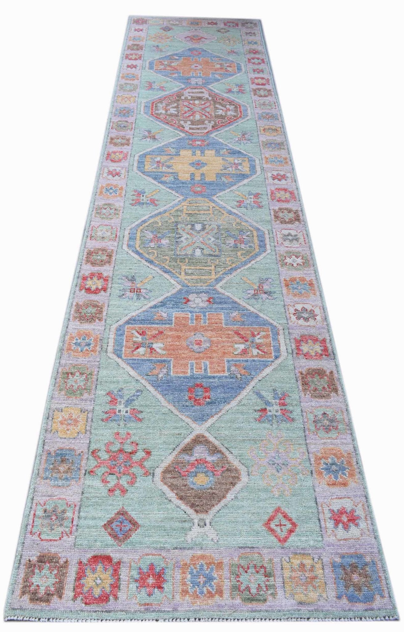 A handwoven transitional Oushak runner rug featuring geometric patterns in soft, muted colors.