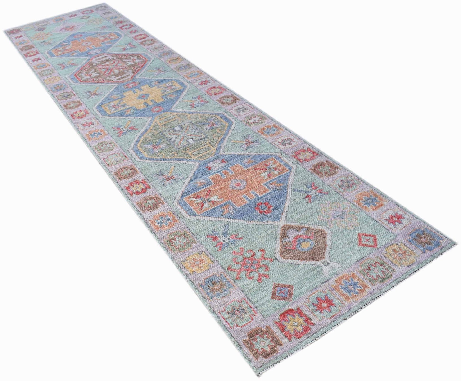 A handwoven wool runner rug featuring a transitional Oushak pattern in soft, multi-colored tones.