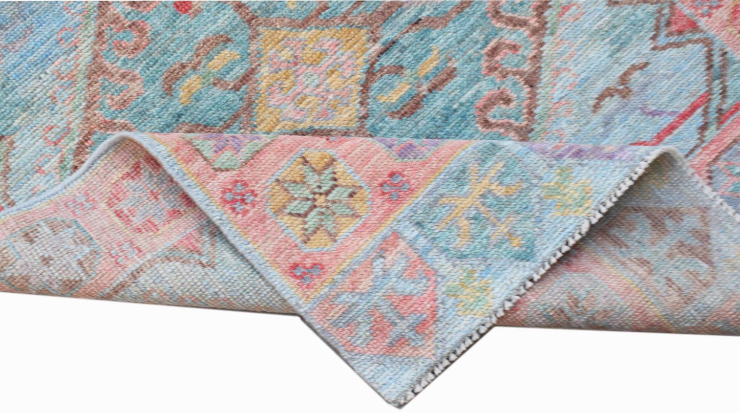 A handwoven wool runner rug featuring a transitional floral pattern in blue, pink, and yellow.