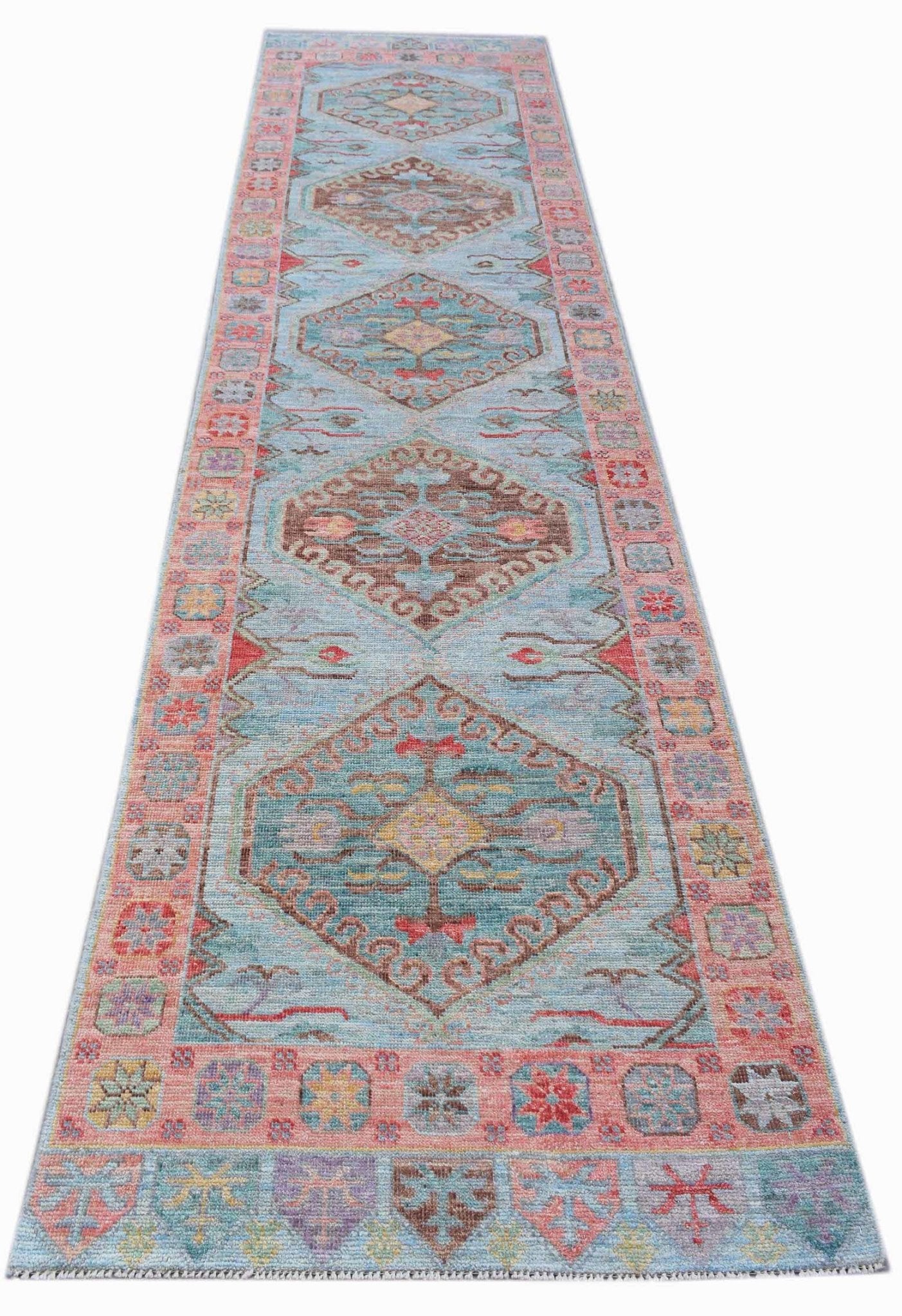 A handwoven transitional Oushak runner featuring geometric medallions on a light blue background.