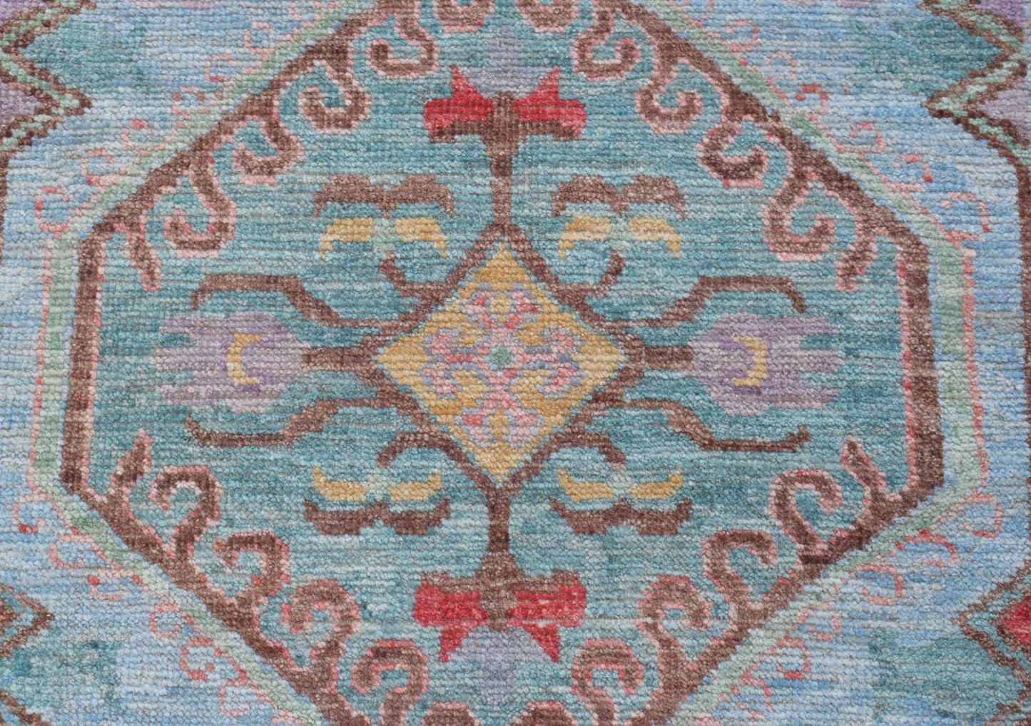 A handwoven transitional Oushak runner featuring a central geometric medallion on a blue field.