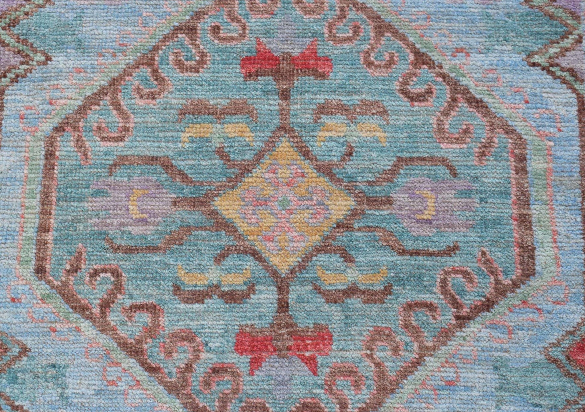 A handwoven transitional Oushak runner featuring a central geometric medallion on a blue field.