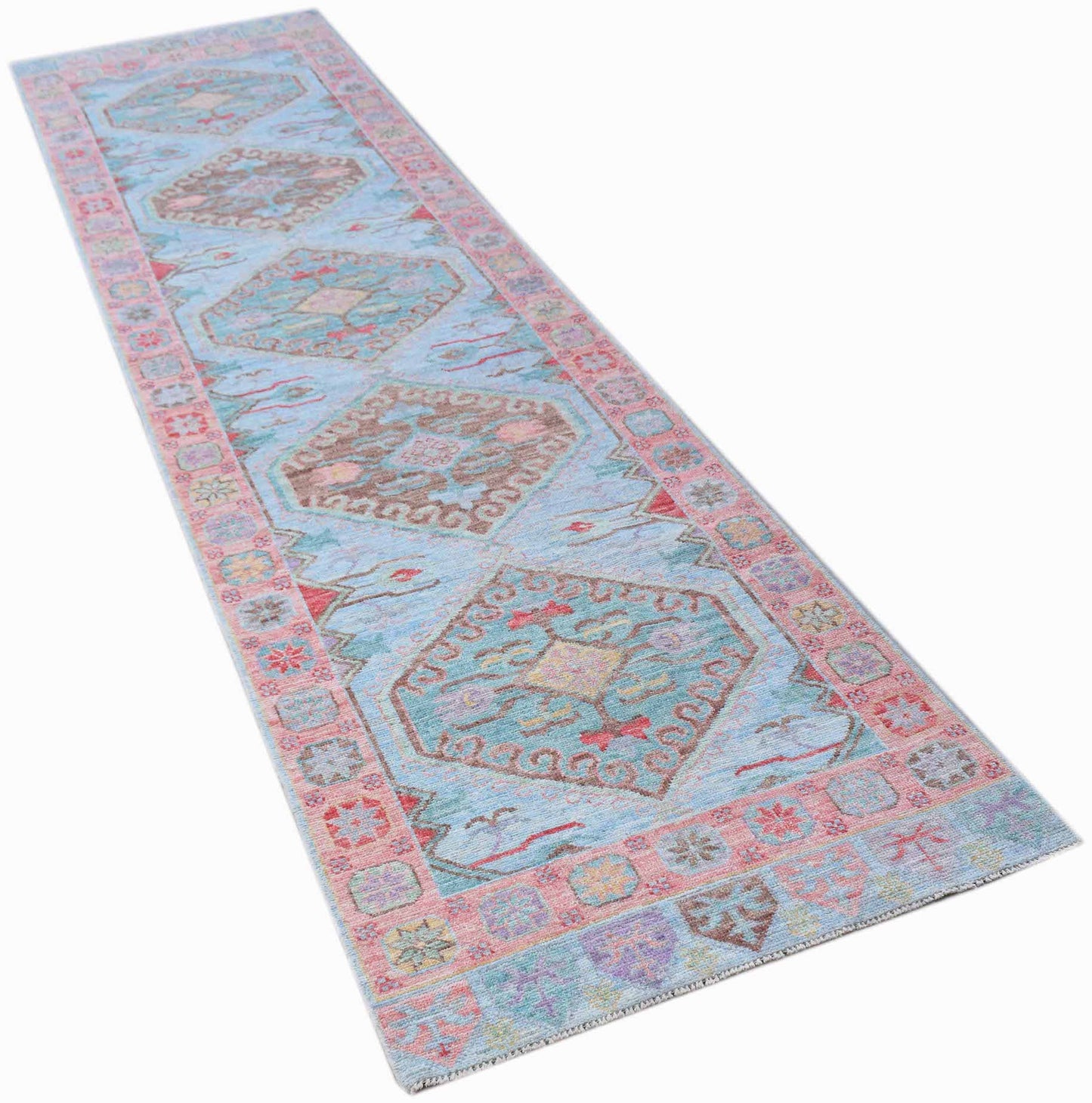 A handwoven transitional Oushak runner featuring geometric medallions on a light blue background.
