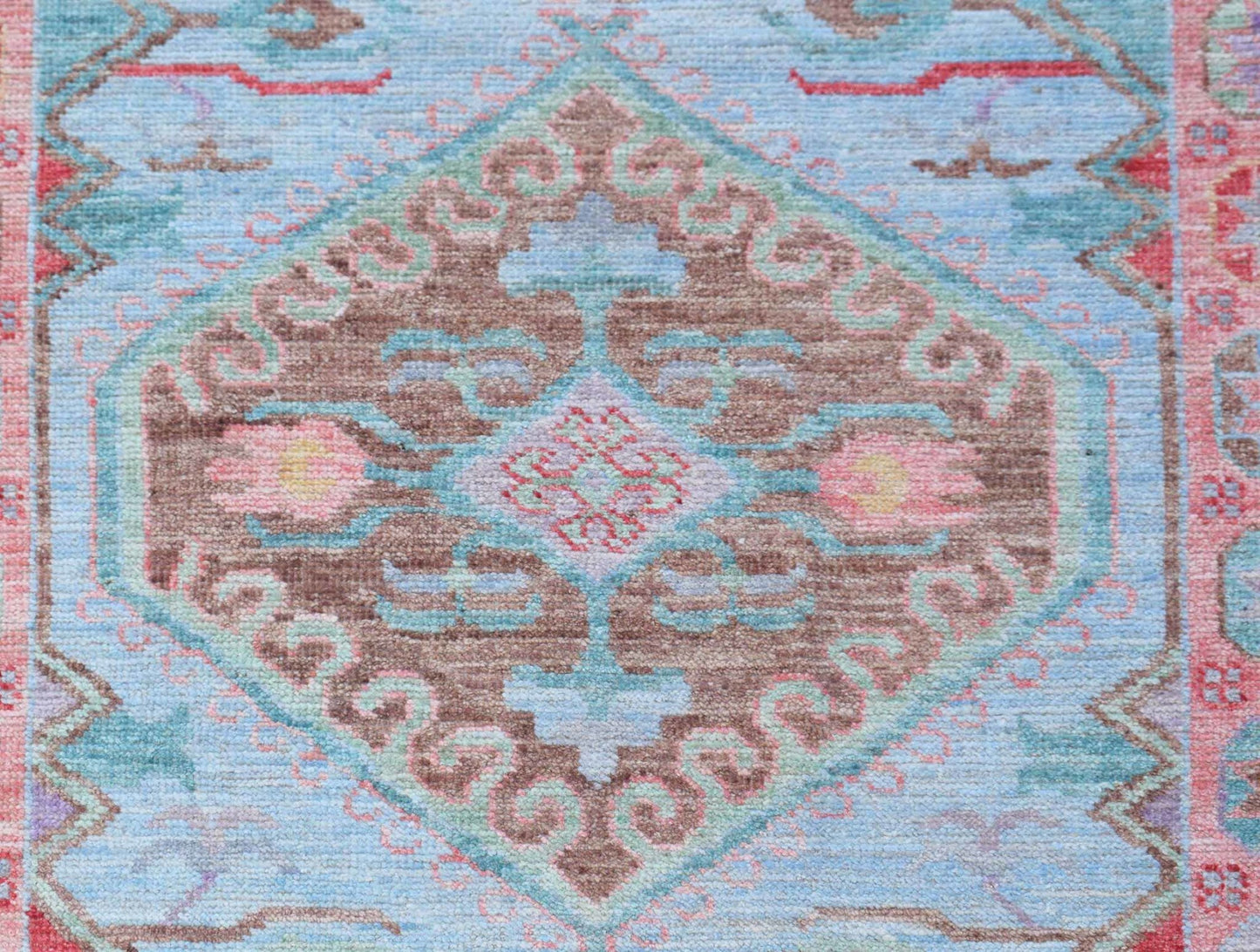 A handwoven transitional Oushak runner featuring a central floral medallion on a light blue field.
