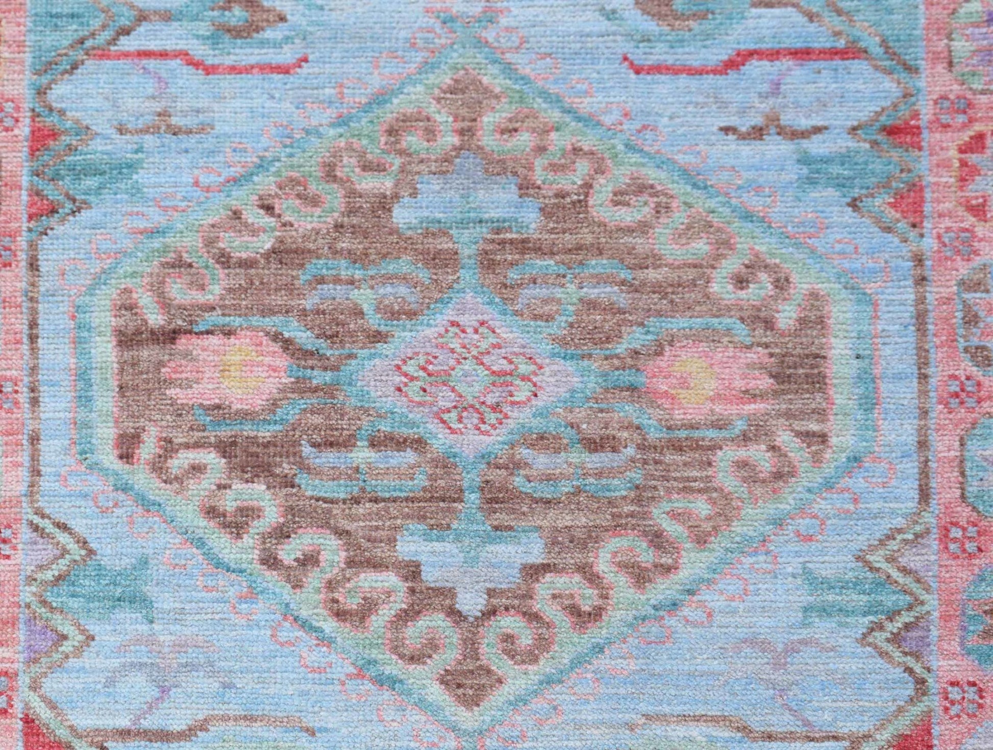 A handwoven transitional Oushak runner featuring a central floral medallion on a light blue field.