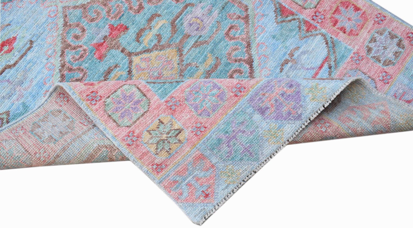 A handwoven transitional Oushak runner featuring a floral pattern in blue, pink, and purple tones.