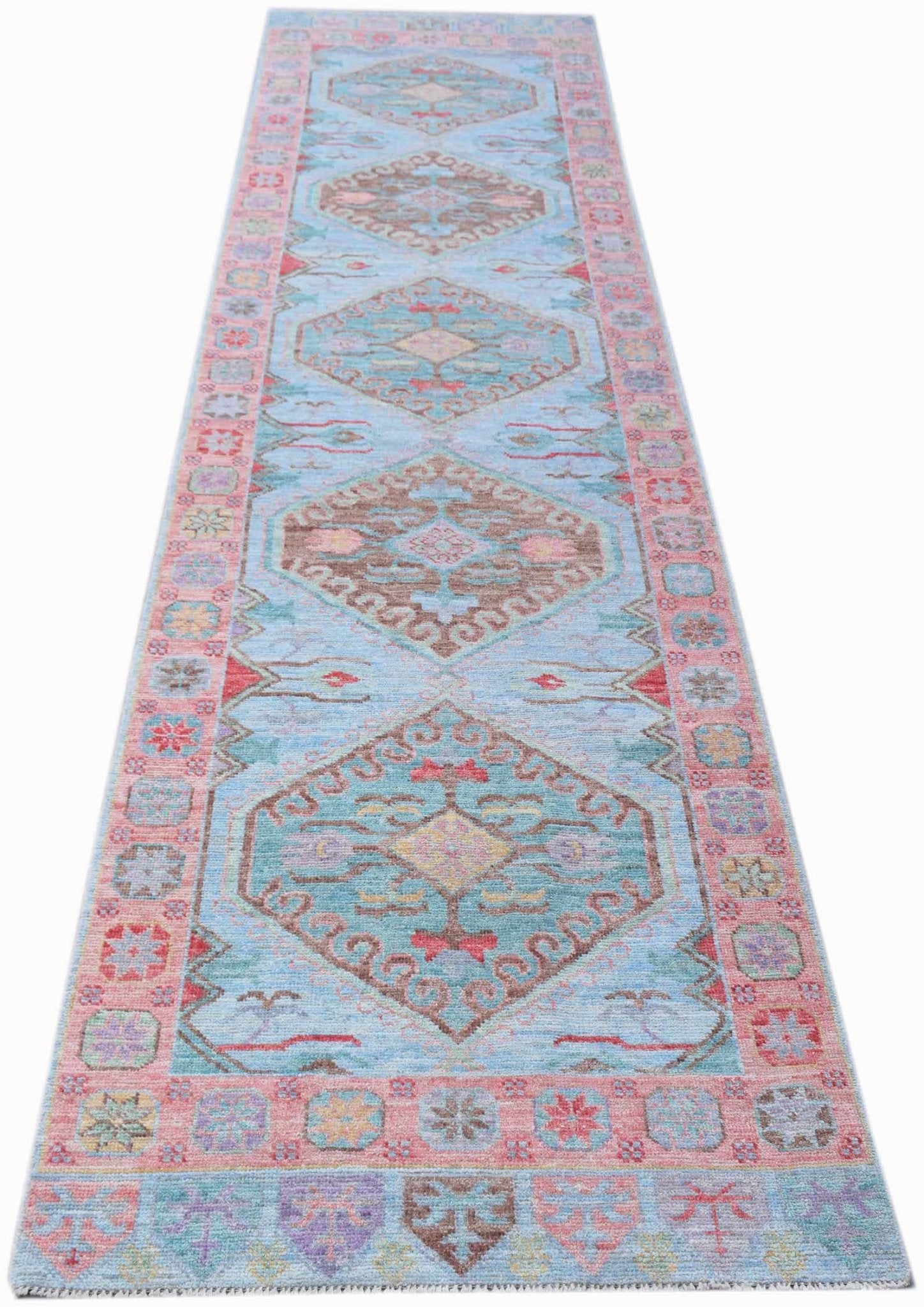 A handwoven transitional Oushak runner rug featuring geometric medallions on a light blue field.