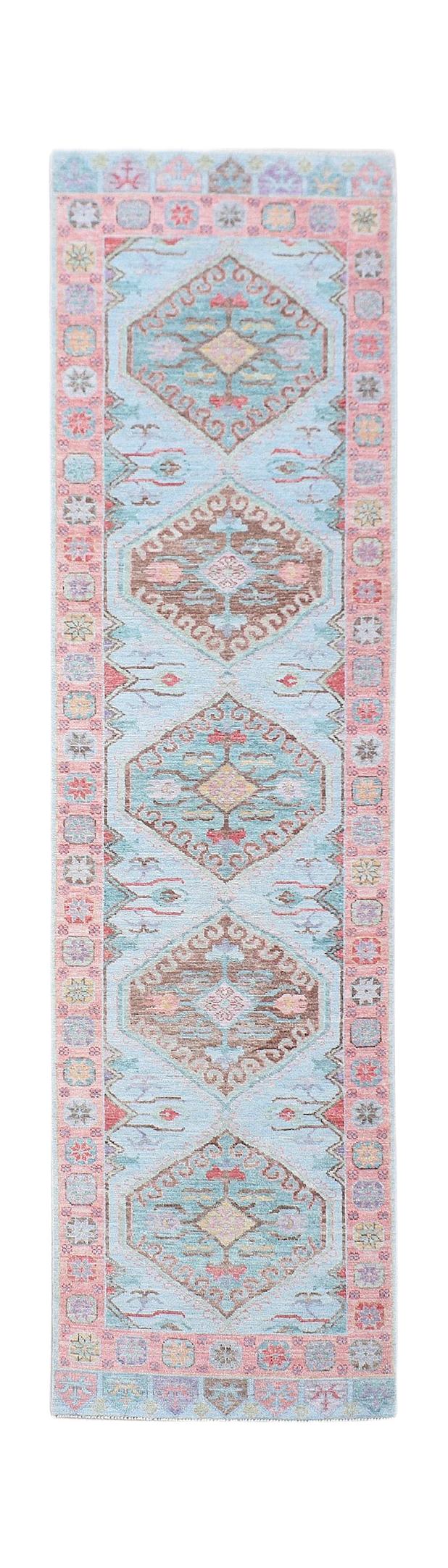 A handwoven wool runner rug featuring a light blue field with repeating geometric floral medallions.