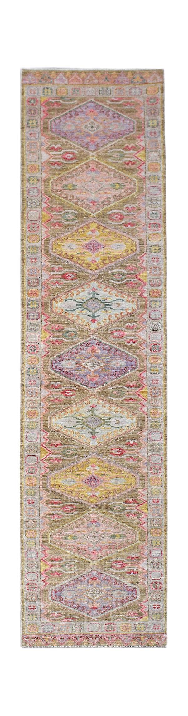 A handwoven wool runner rug featuring a repeating diamond pattern in soft, multicolored tones.