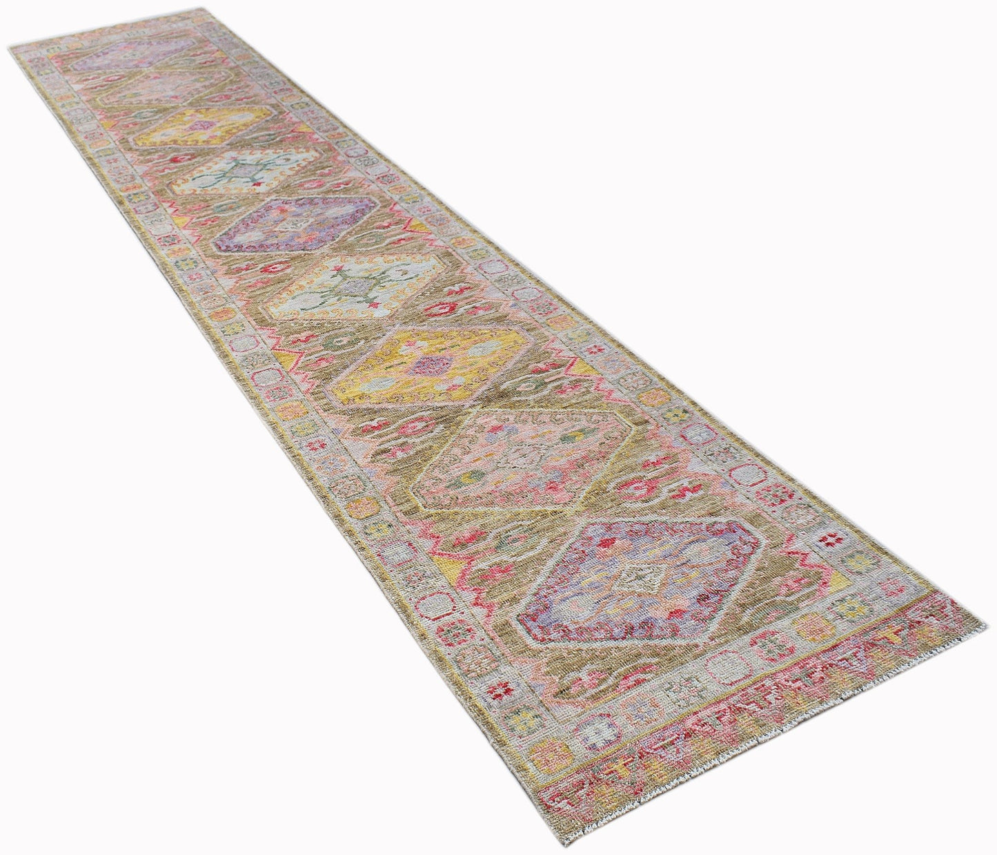A long, handwoven wool runner rug featuring a transitional Oushak pattern in muted, colorful tones.