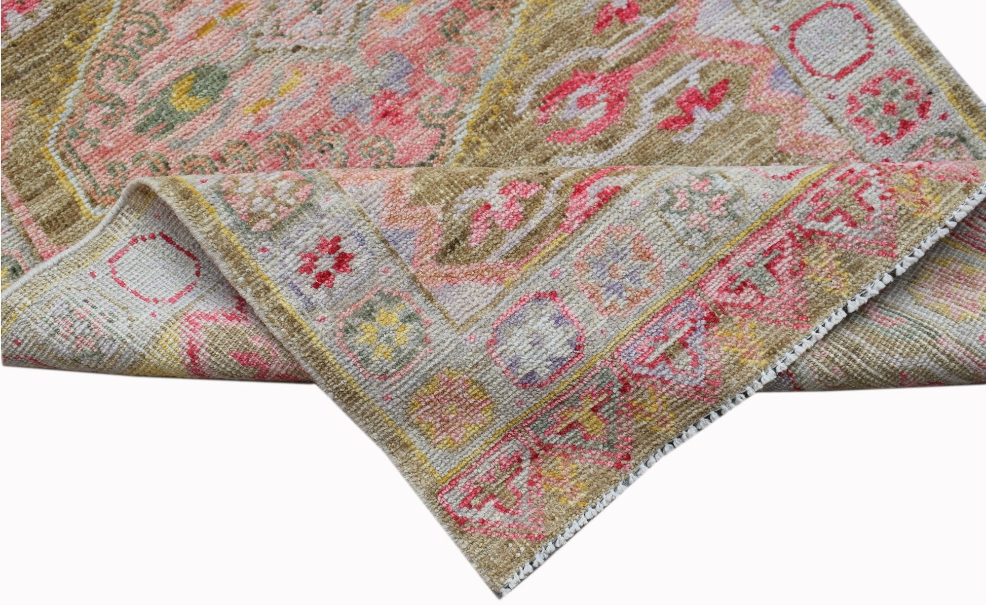 A handwoven Oushak runner featuring a floral pattern in pink, yellow, and tan tones.