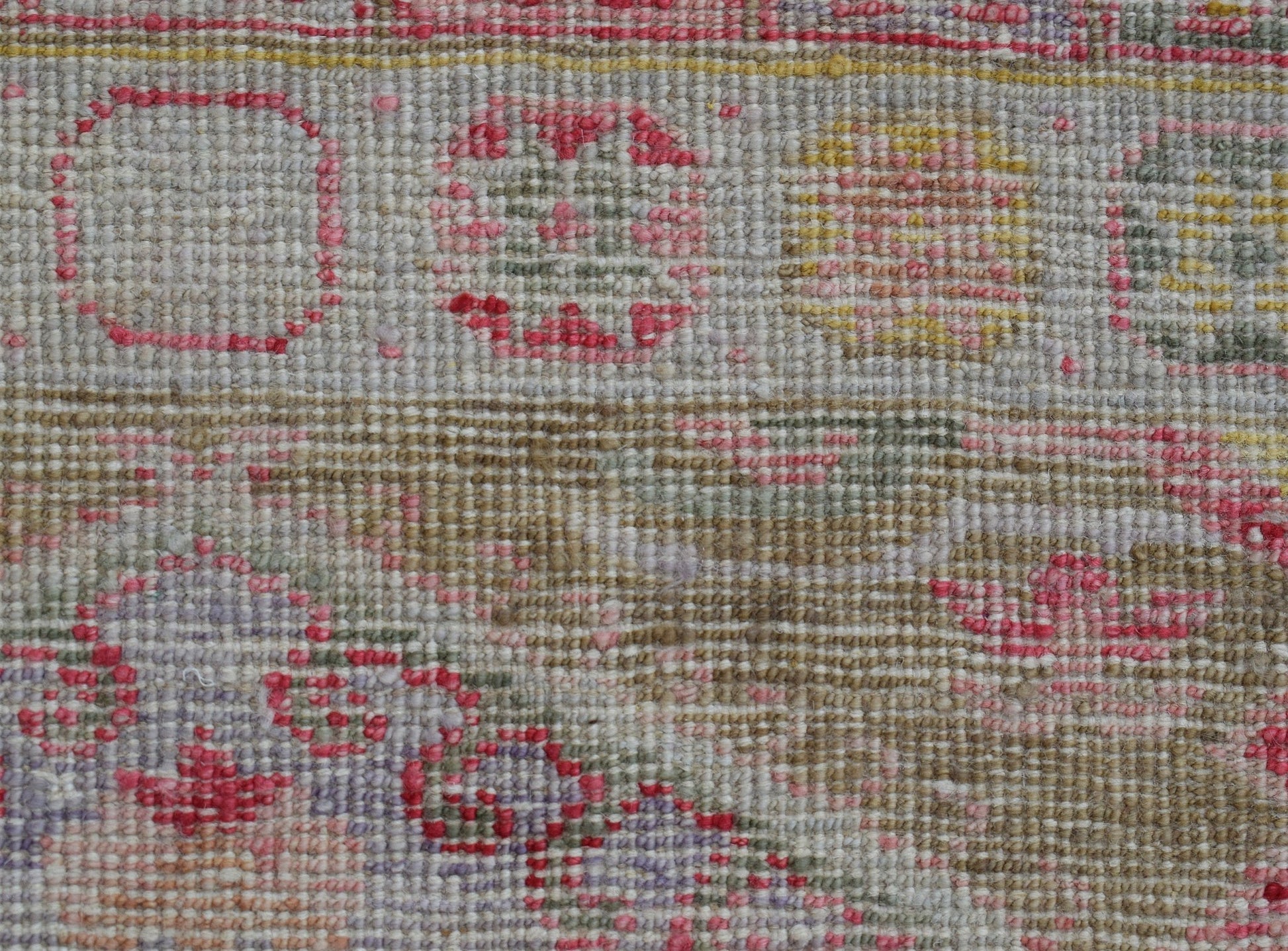 A close-up of a handwoven Oushak runner featuring a textured pattern in pink, yellow, and grey.