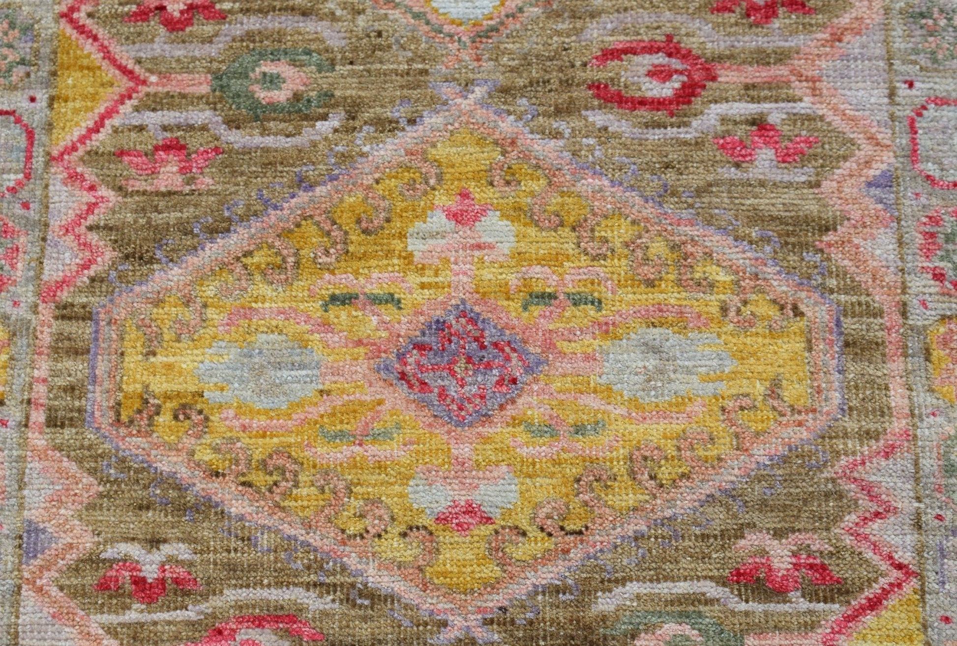A handwoven wool runner featuring a central yellow diamond medallion with floral motifs.