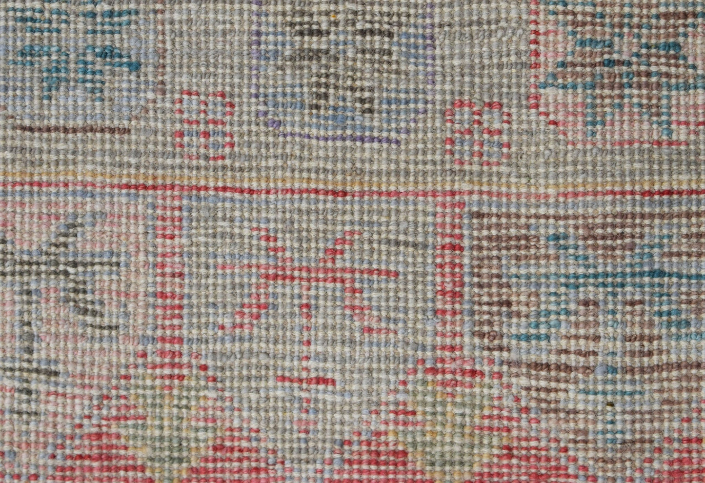A close-up of a handwoven wool runner featuring a transitional pattern in muted tones.
