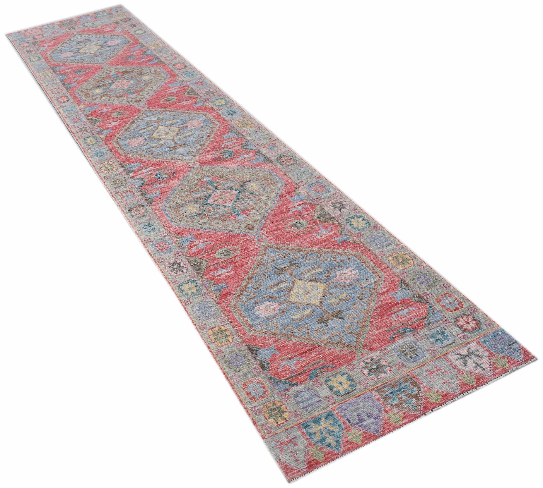 A handwoven wool runner rug featuring a traditional Oushak pattern in red, blue, and yellow tones.
