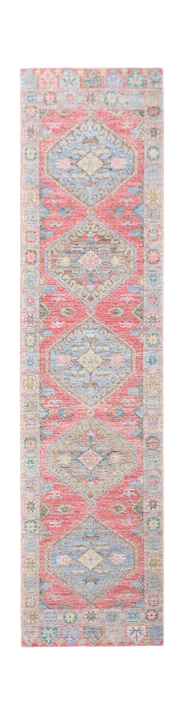 A handwoven wool runner rug featuring a repeating diamond pattern in red, blue, and muted tones.