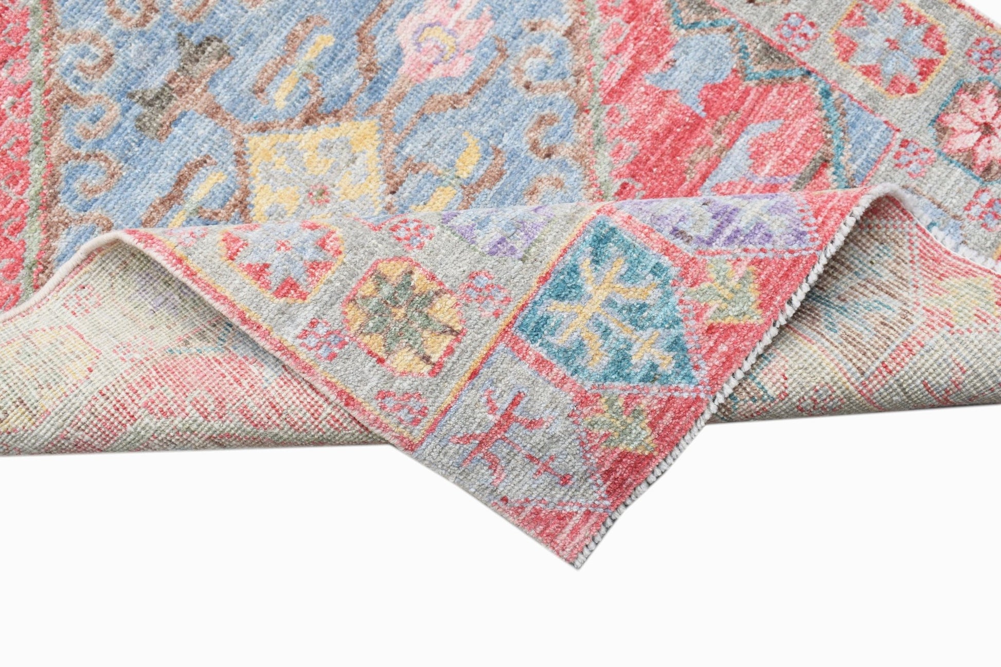 A handwoven transitional Oushak runner featuring a floral pattern in blue, red, and yellow tones.