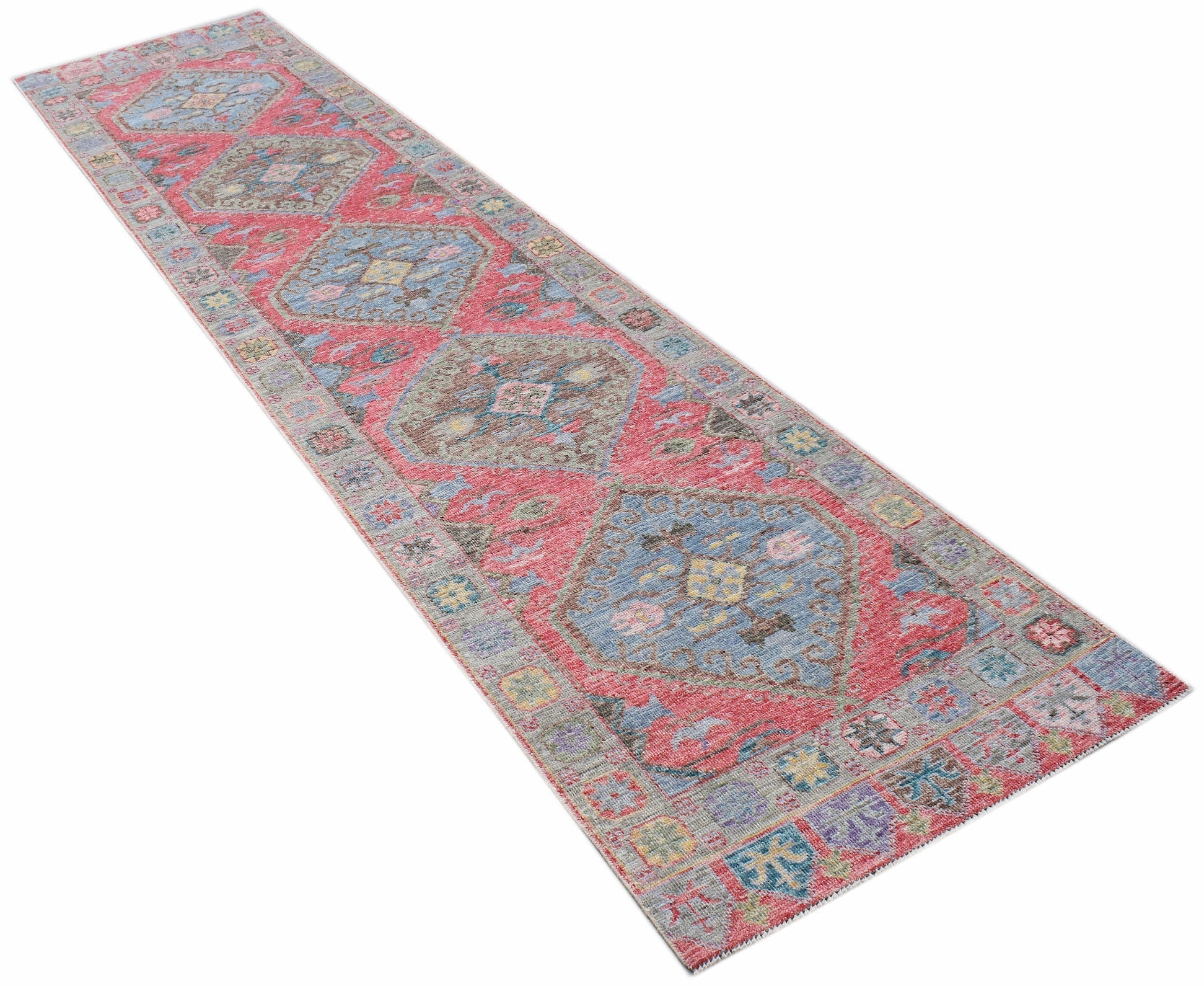 A handwoven wool runner rug featuring a traditional Oushak pattern in red, blue, and grey tones.
