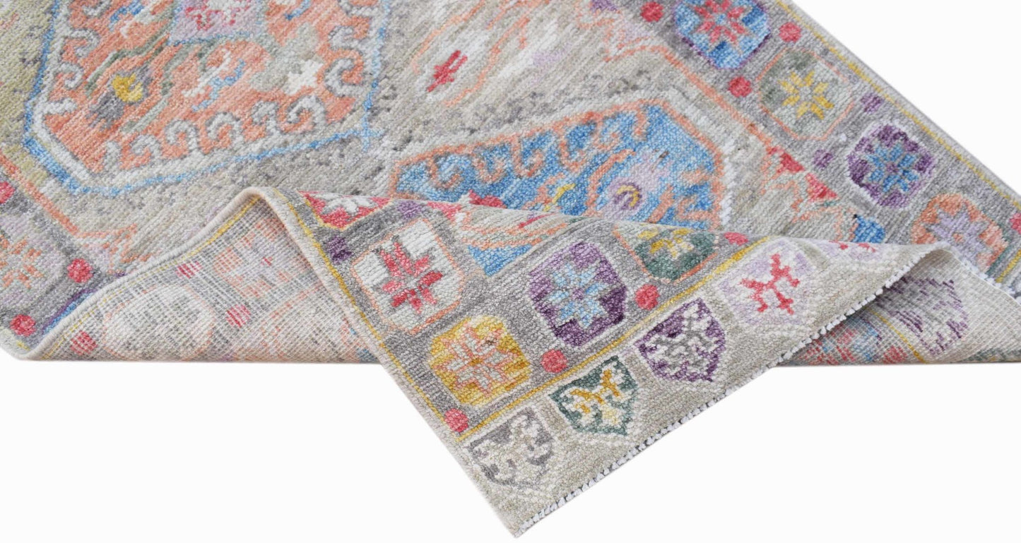 A handwoven transitional Oushak rug featuring a colorful floral pattern on a light gray background.