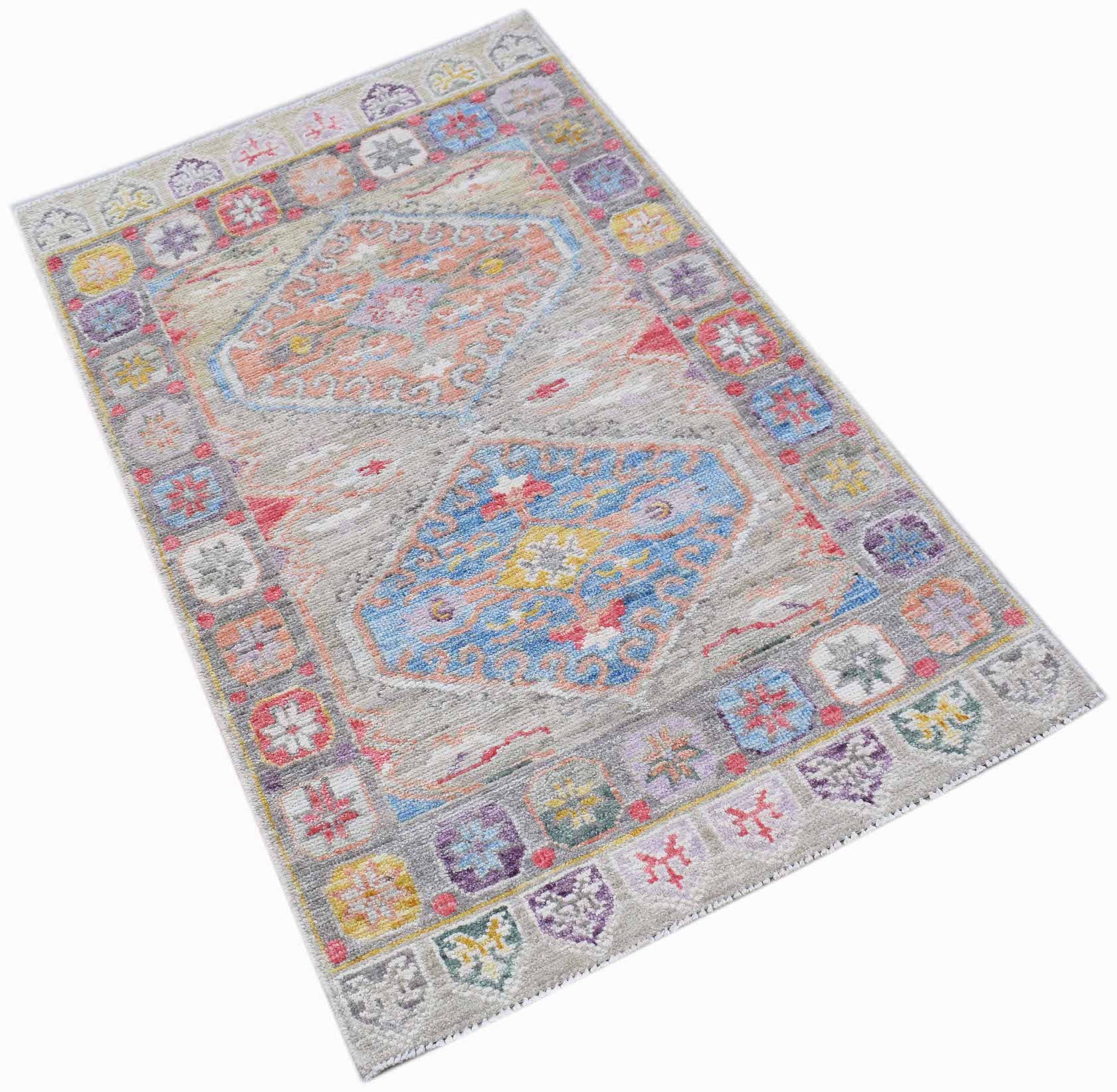 A handwoven transitional Oushak rug featuring a grey field with two colorful geometric medallions.