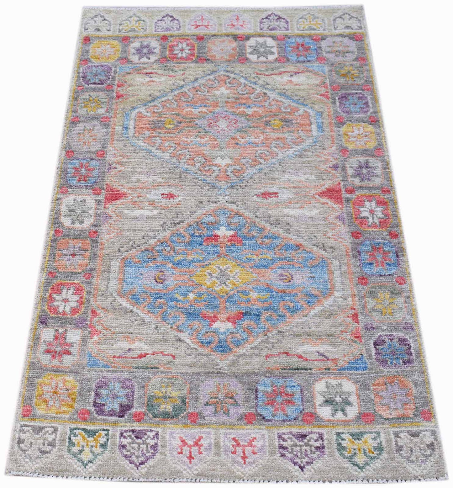 A handwoven transitional Oushak rug featuring a grey field with colorful geometric medallions.