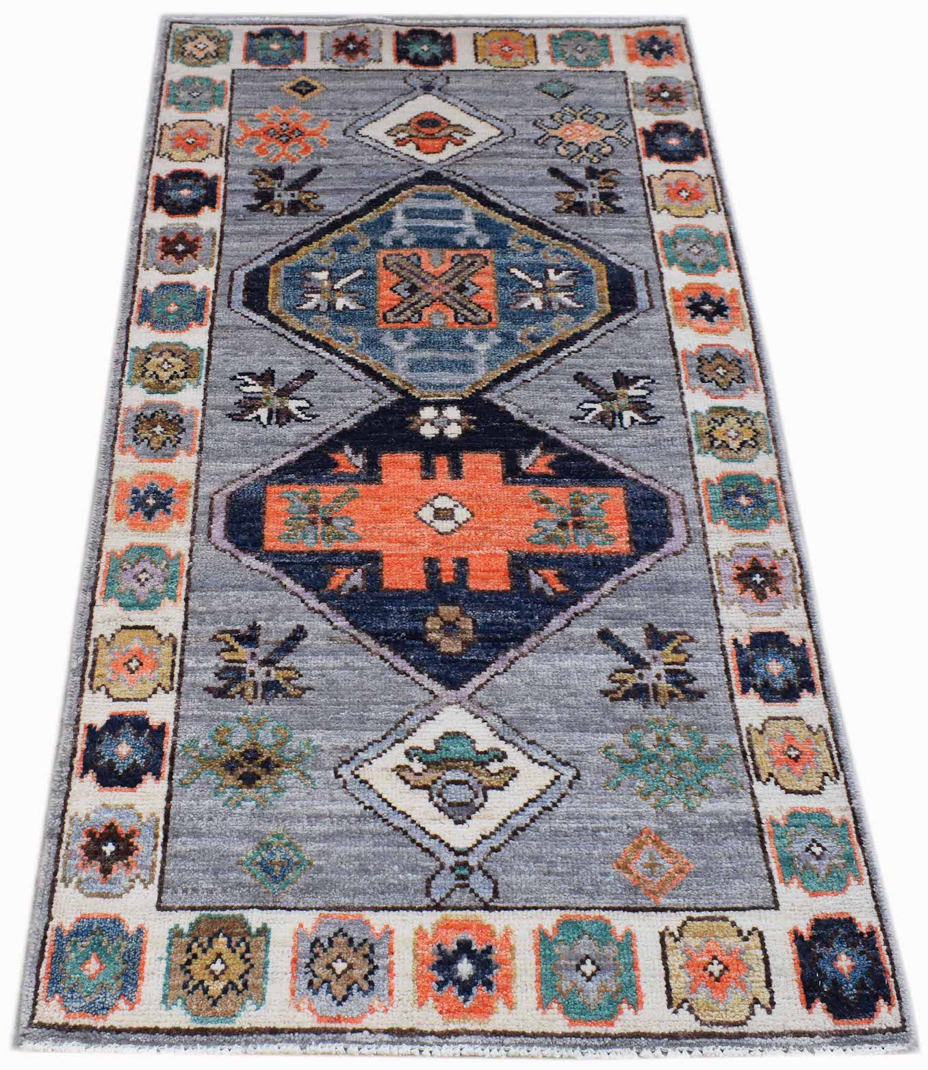 A handwoven transitional Oushak rug featuring geometric patterns in blue, orange, and grey tones.