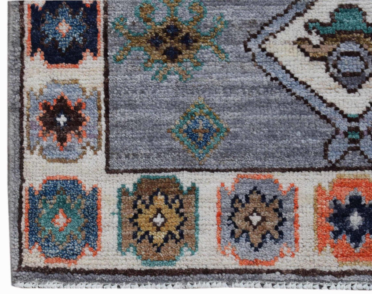 A handwoven transitional Oushak rug featuring a grey field with colorful geometric floral motifs.