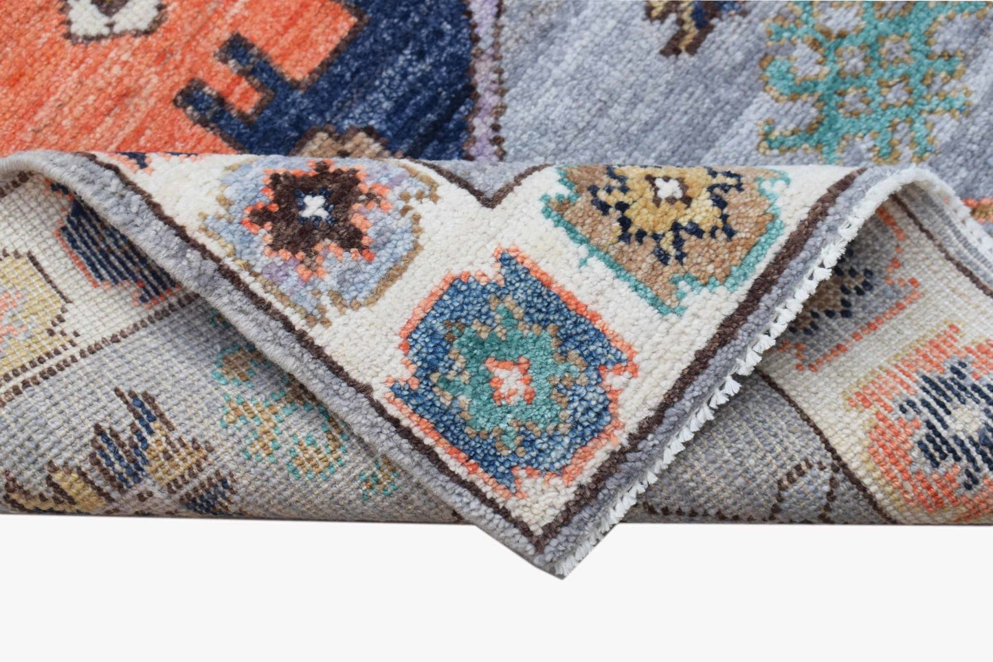 A handwoven transitional Oushak rug featuring a colorful geometric pattern on a light gray background.
