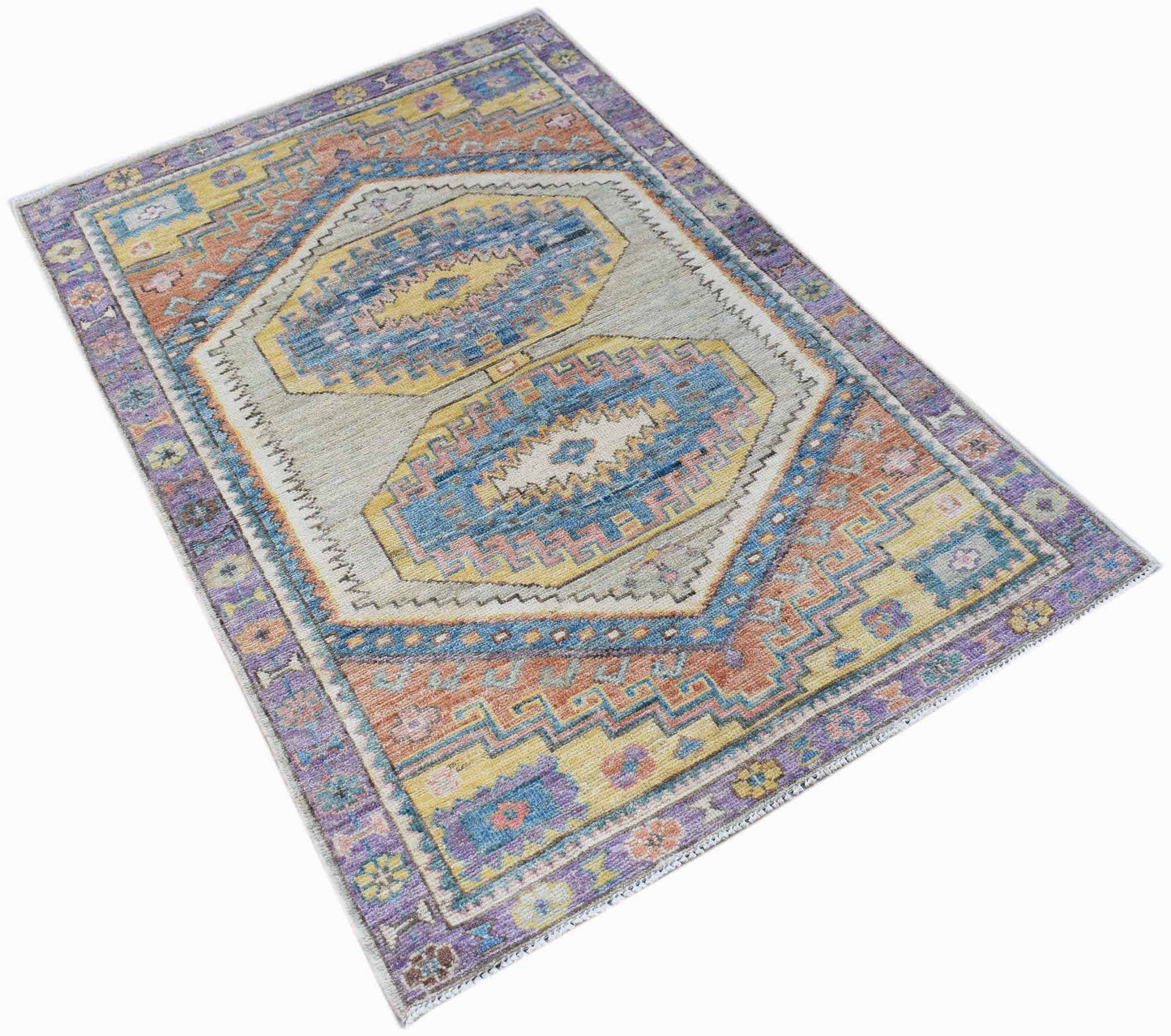 A handwoven transitional Oushak rug featuring a geometric pattern in blue, yellow, and purple.