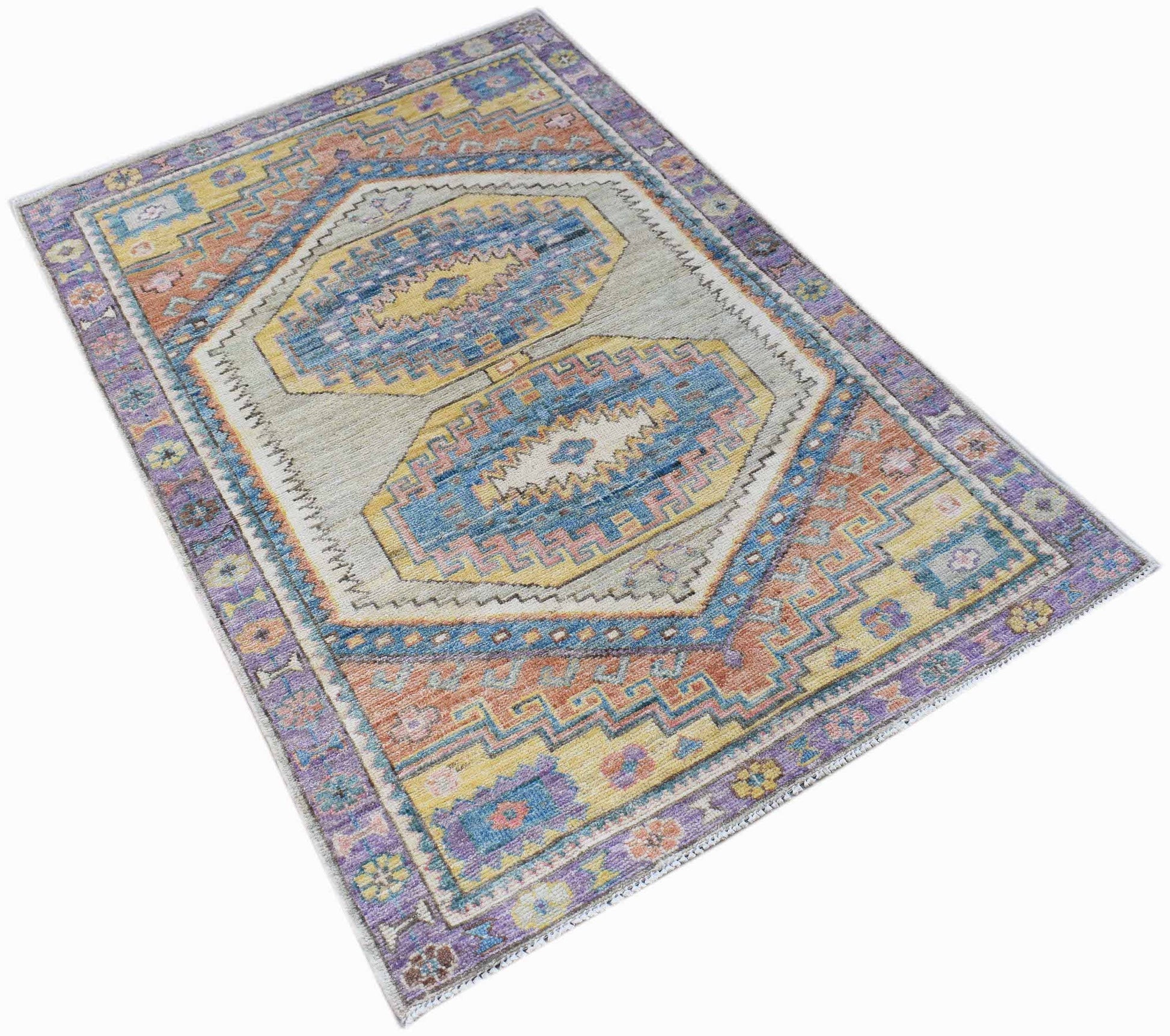 A handwoven transitional Oushak rug featuring a geometric pattern in blue, yellow, and purple.