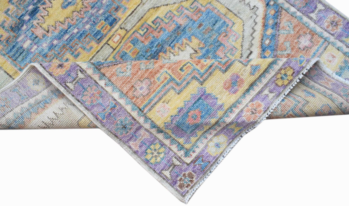 A handwoven transitional Oushak rug featuring a colorful geometric and floral pattern.