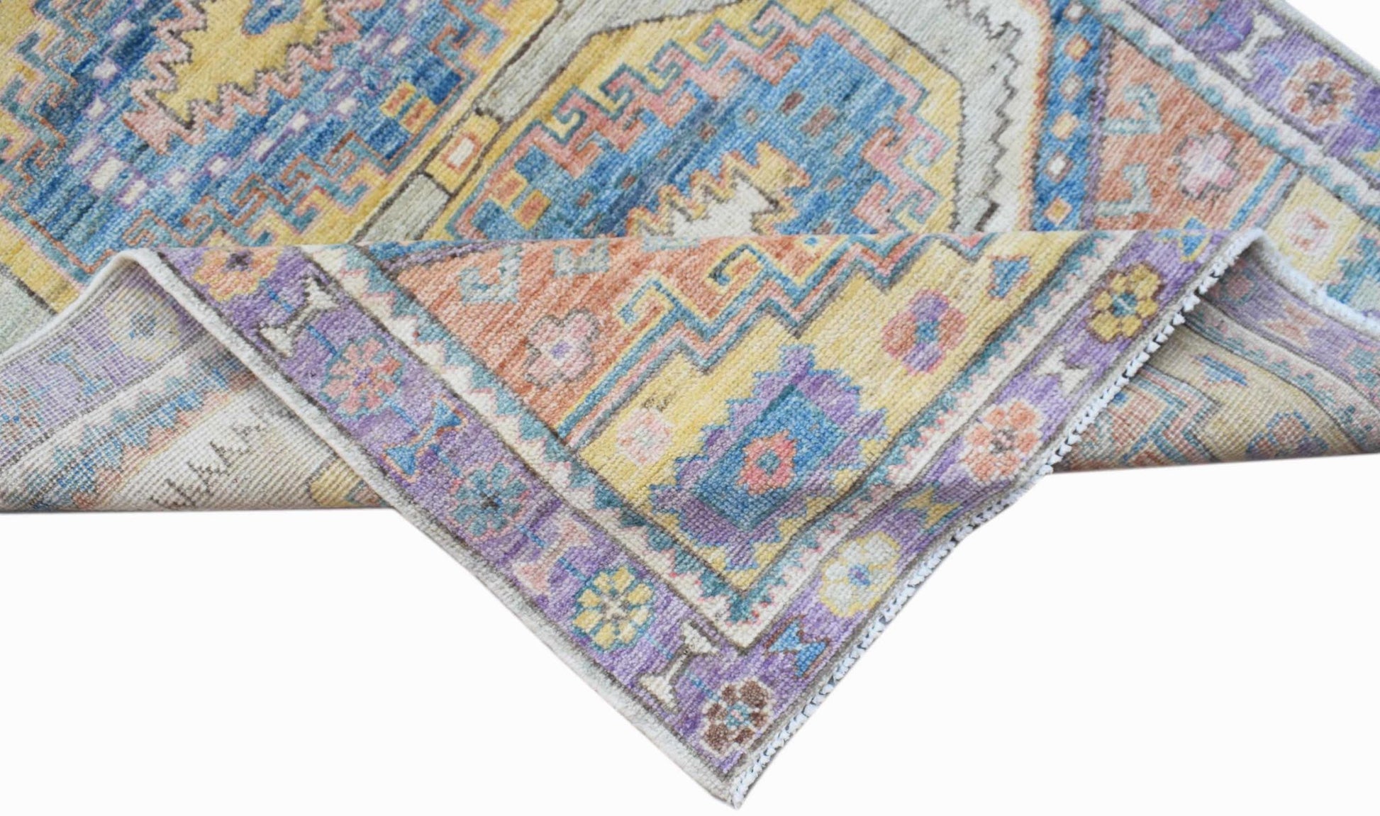 A handwoven transitional Oushak rug featuring a colorful geometric and floral pattern.