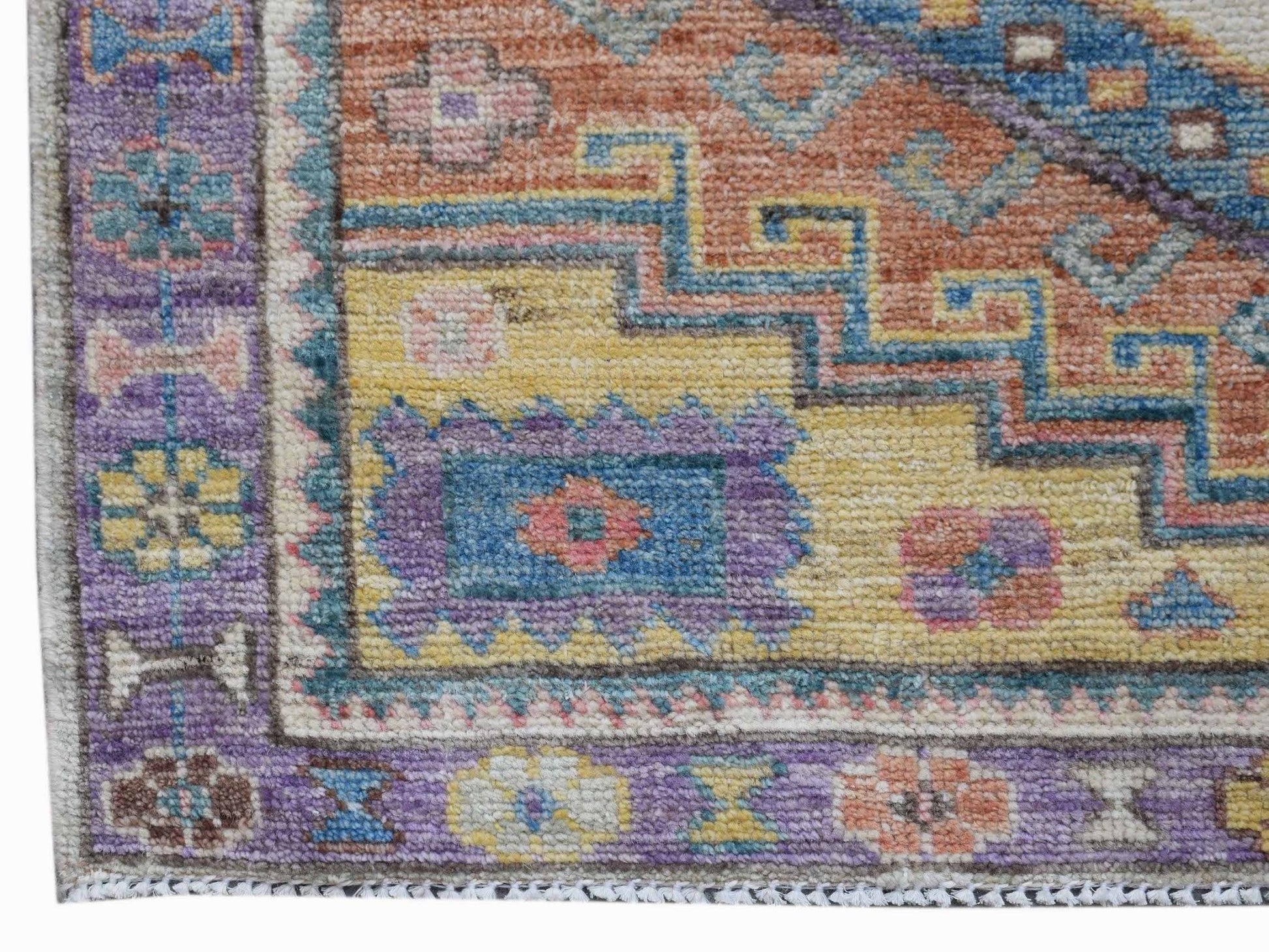 A handwoven transitional Oushak rug featuring a geometric floral pattern in vibrant colors.