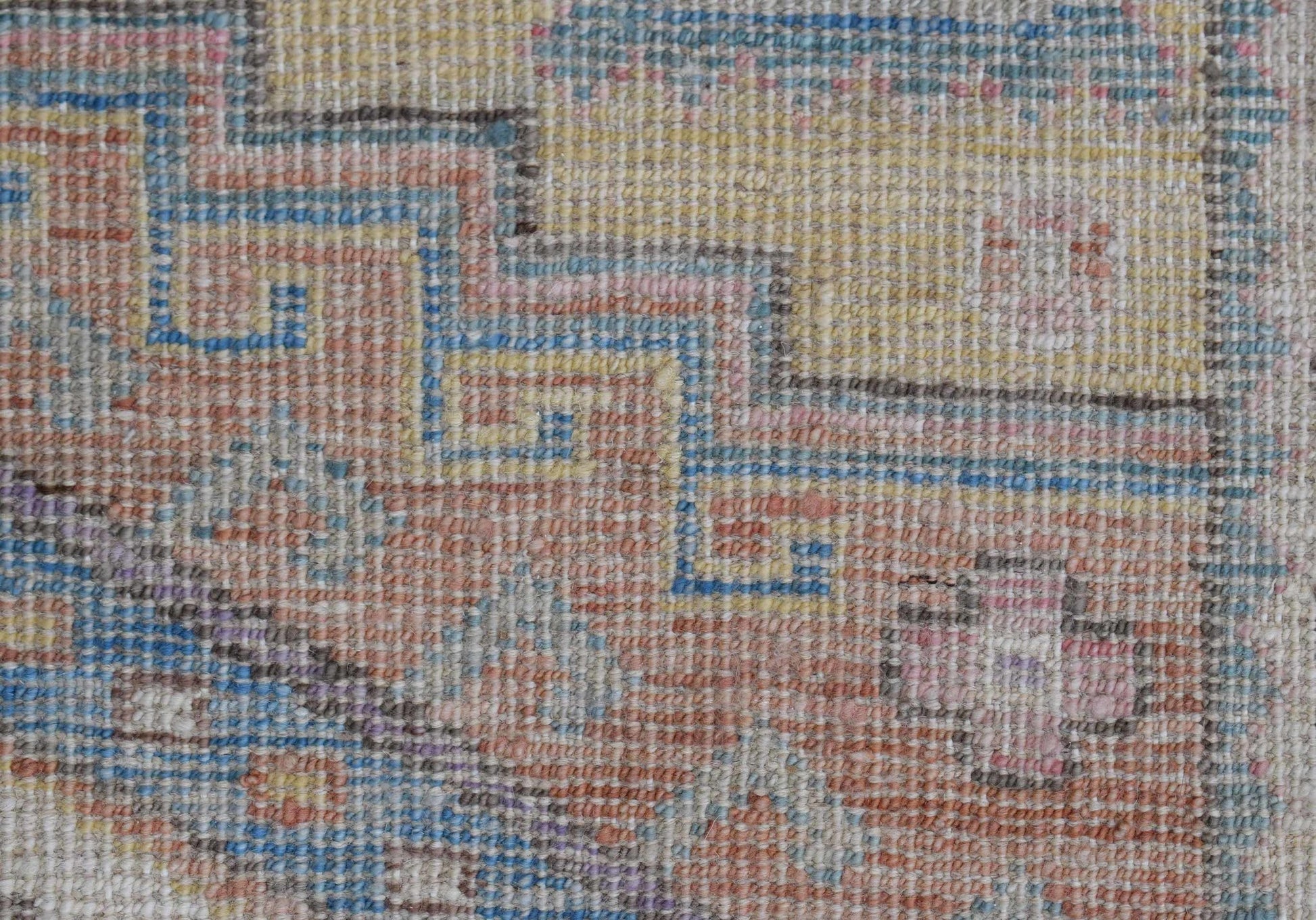 A handwoven transitional Oushak rug featuring a geometric pattern in soft, muted tones.