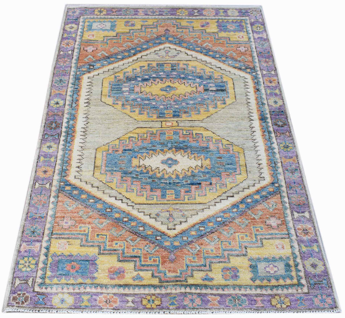 A handwoven transitional Oushak rug featuring a geometric pattern in blue, yellow, and orange.