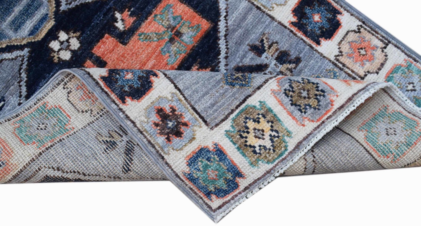 A handwoven transitional Oushak rug featuring a geometric floral pattern in blue and orange tones.